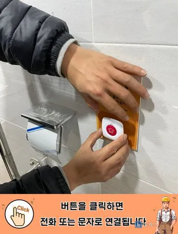 타일 벽에 도움벨 안내판과 비상벨 버튼을 대어 위치를 잡는 모습