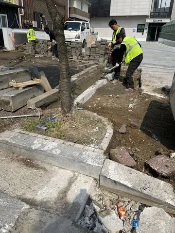 안전조끼를 입은 작업자들이 경계석 자리를 잡고 보도블럭을 철거하는 모습