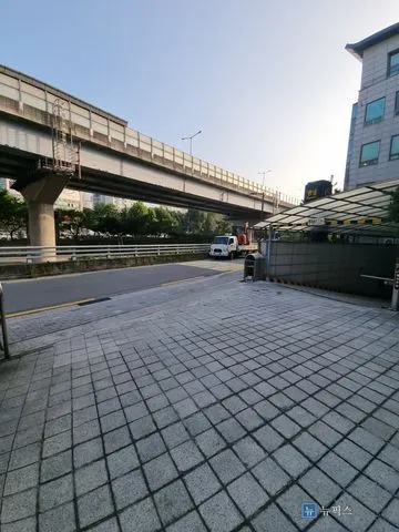 고가도로 옆 상가 건물 지하주차장 출입구와 석재 포장 바닥