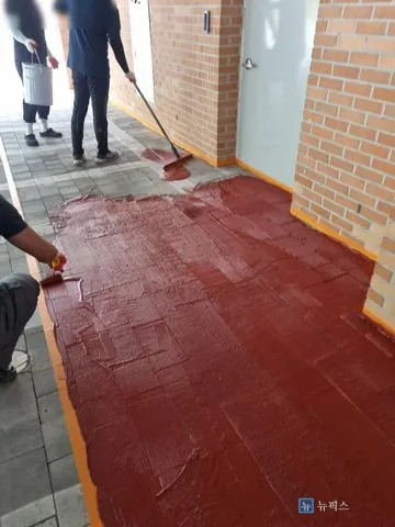 작업자 세 명이 MMA를 레키로 밀어 펴고 있는 장면