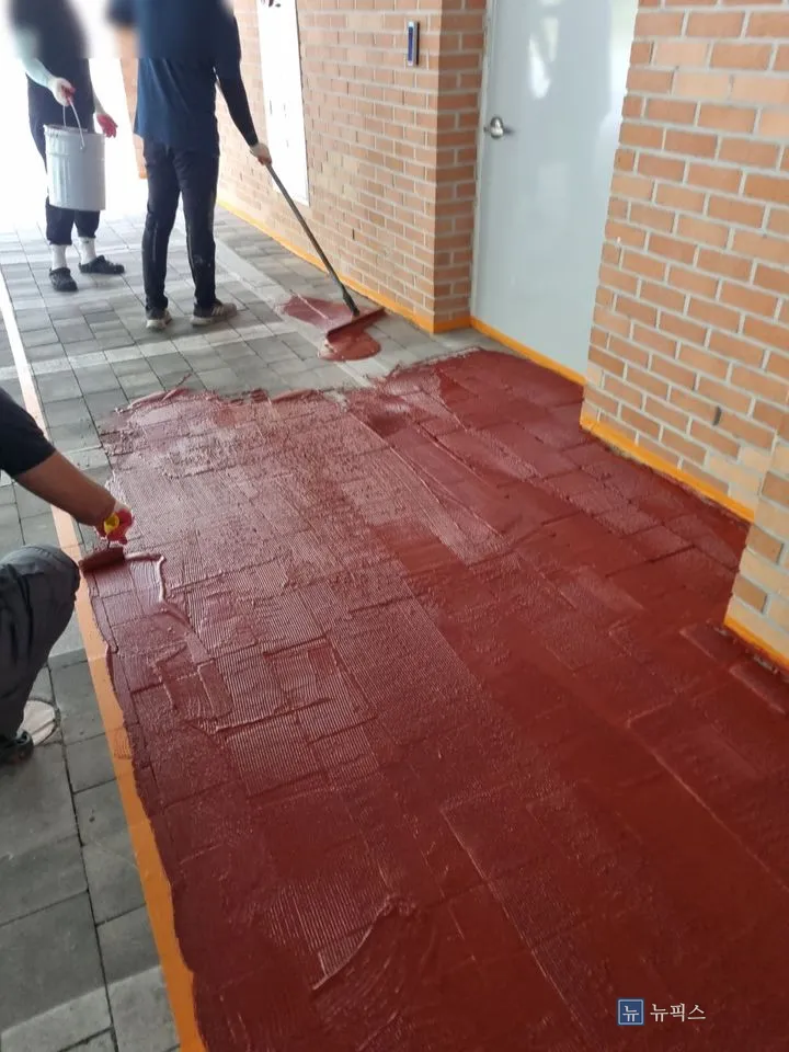 작업자 세 명이 MMA를 레키로 밀어 펴고 있는 장면