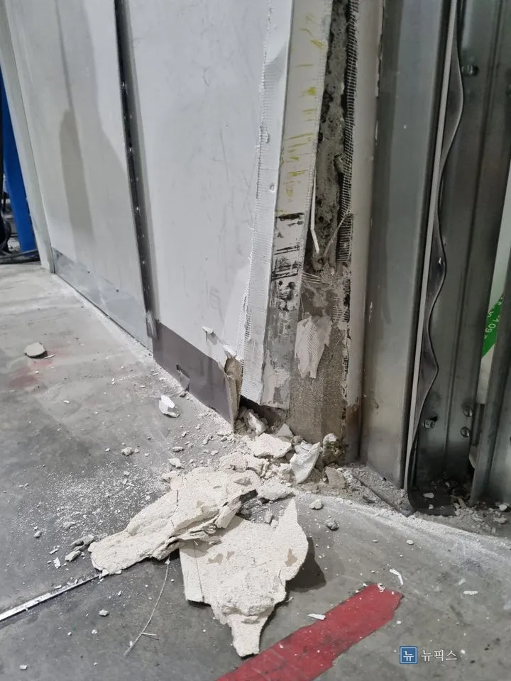 지게차 충돌로 석고보드가 깨져 조각이 바닥에 쏟아진 창고 입구 벽