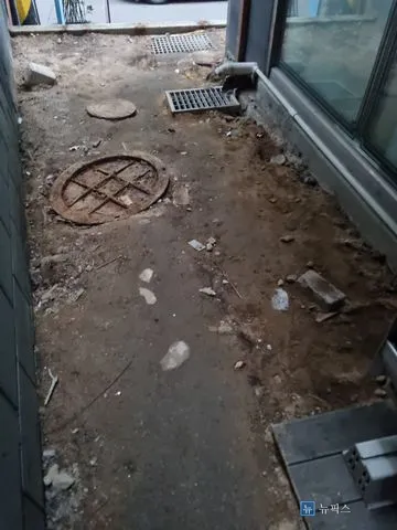 잔해가 흩어진 빌라 옆 샛길 흙바닥과 맨홀 뚜껑