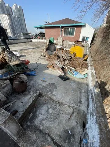 폐기물과 나뭇가지가 쌓여 있는 시공 전 주택 옥상
